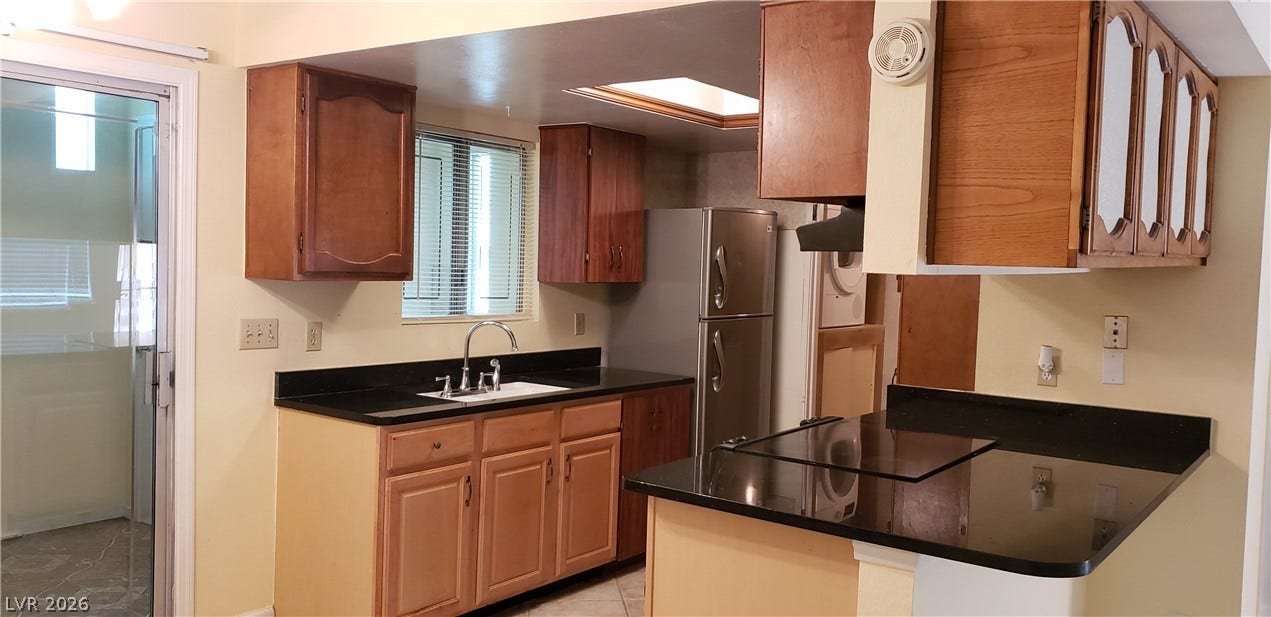 Rich wood cabinets and dark stone counters define this functional cooking space with a skylight.