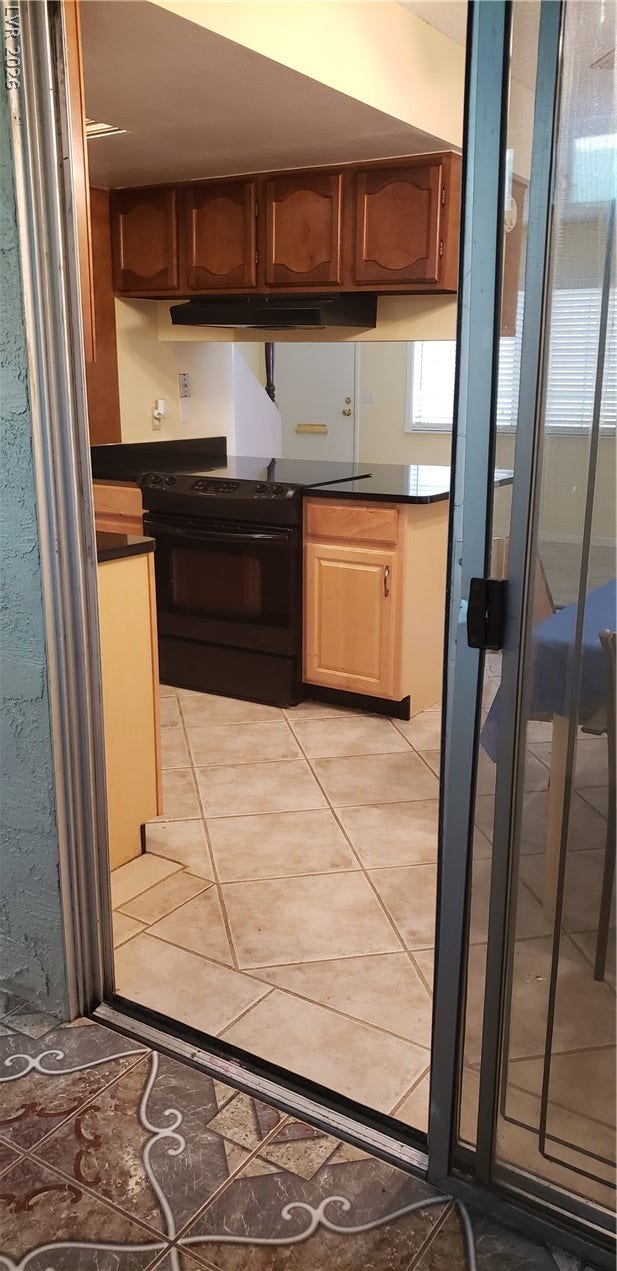 A sliding glass door opens to tile flooring and structured wooden cabinetry.