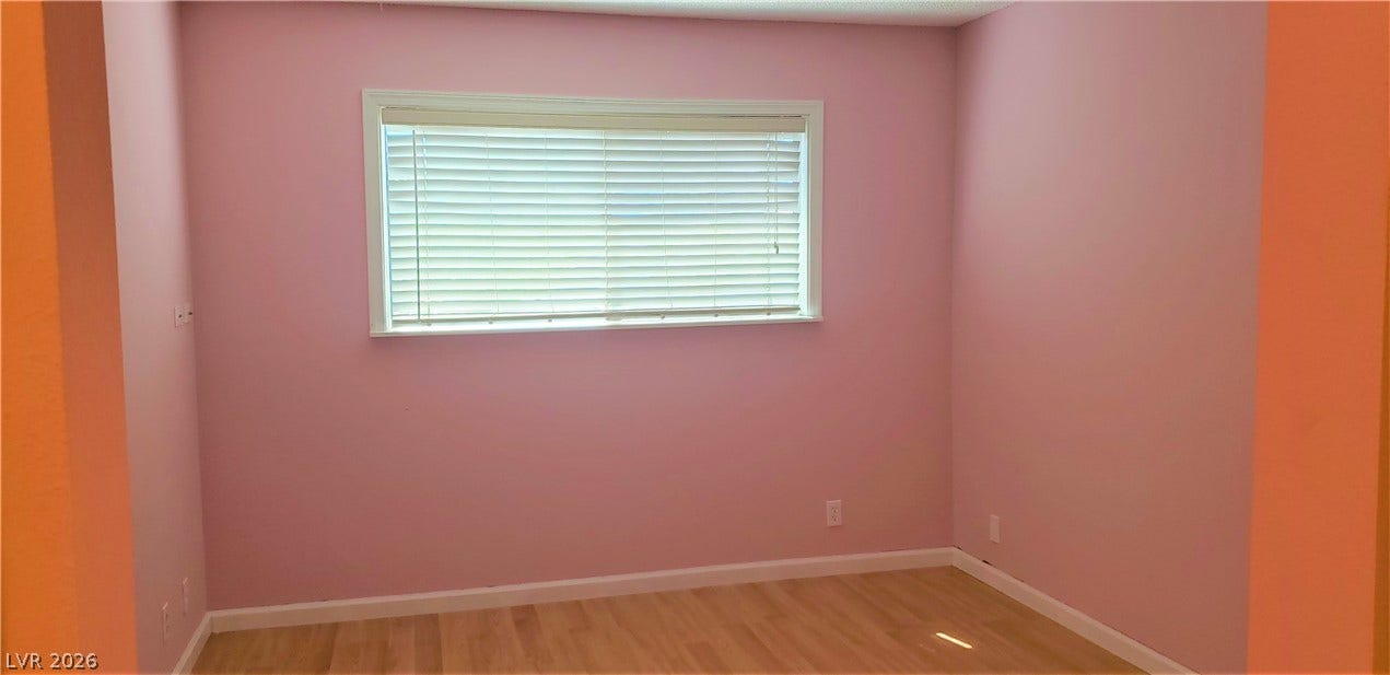 Natural light streams through a wide window onto smooth hardwood flooring.