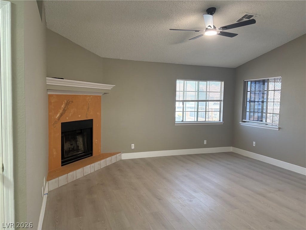 A classic corner fireplace anchors this open living space highlighted by vaulted ceilings and wood floors.