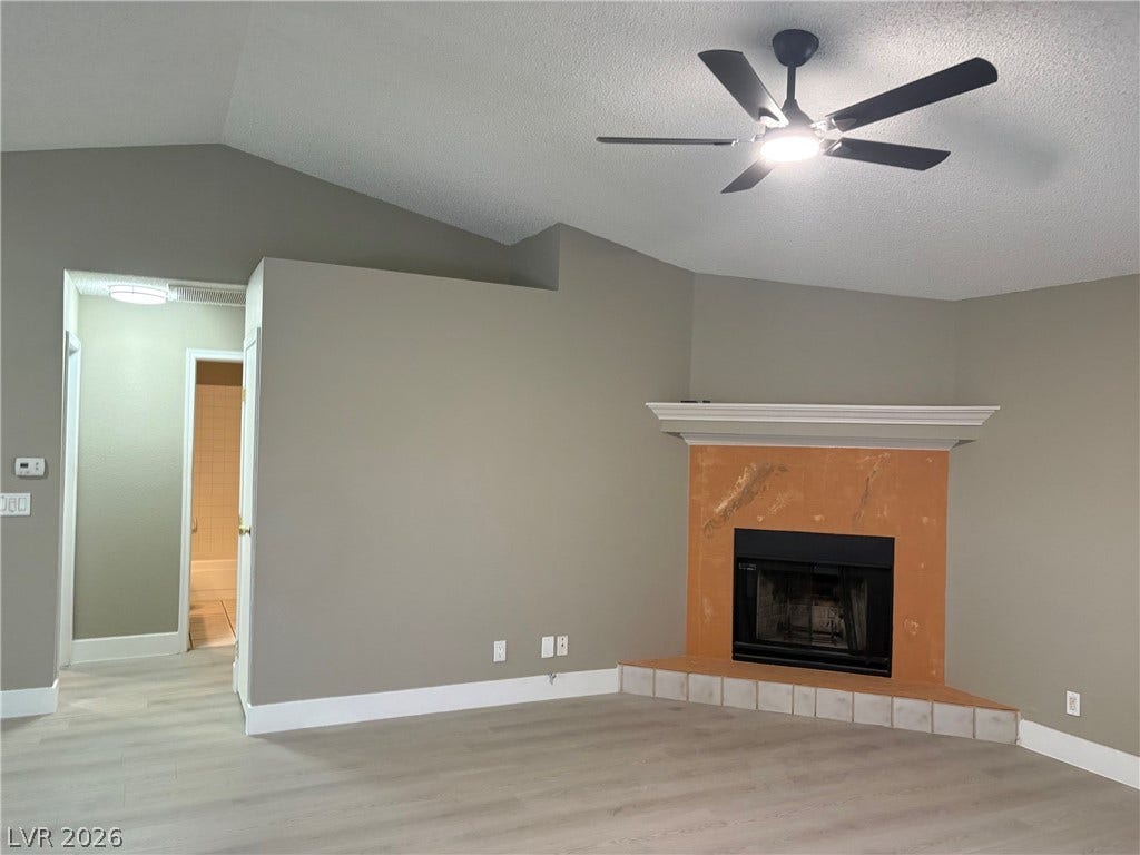 A classic fireplace and a vaulted ceiling anchor this inviting space with durable luxury vinyl plank flooring.
