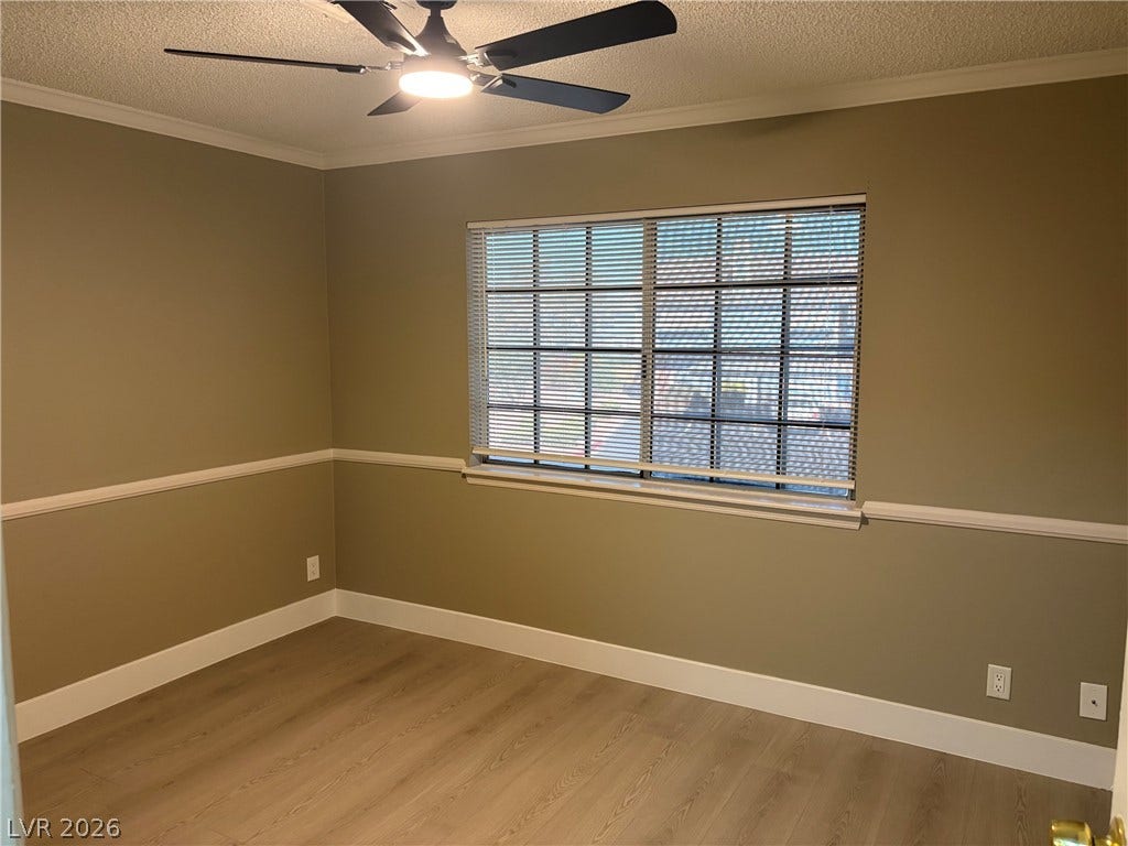 Elegant crown molding and classic wainscoting frame this versatile bedroom space featuring warm wood flooring.