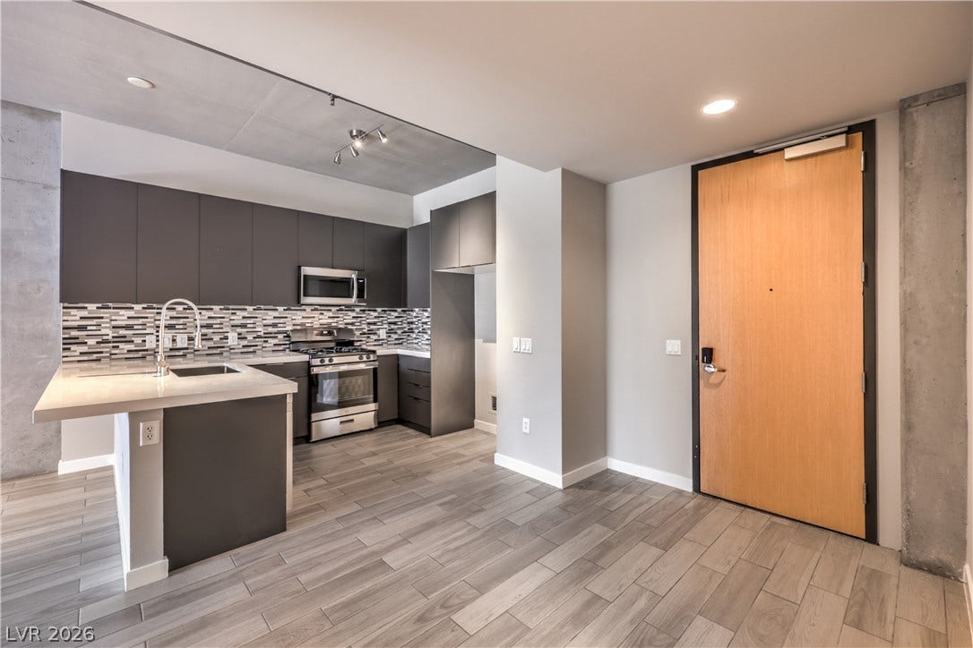 353 E Bonneville Avenue, #754, Las Vegas, NV 89101 Sleek Modern Kitchen features Quartz Countertops, Decorative Tile Backslash, Breakfast Bar, Stainless-Steel Gas Range, Dishwasher, and Microwave