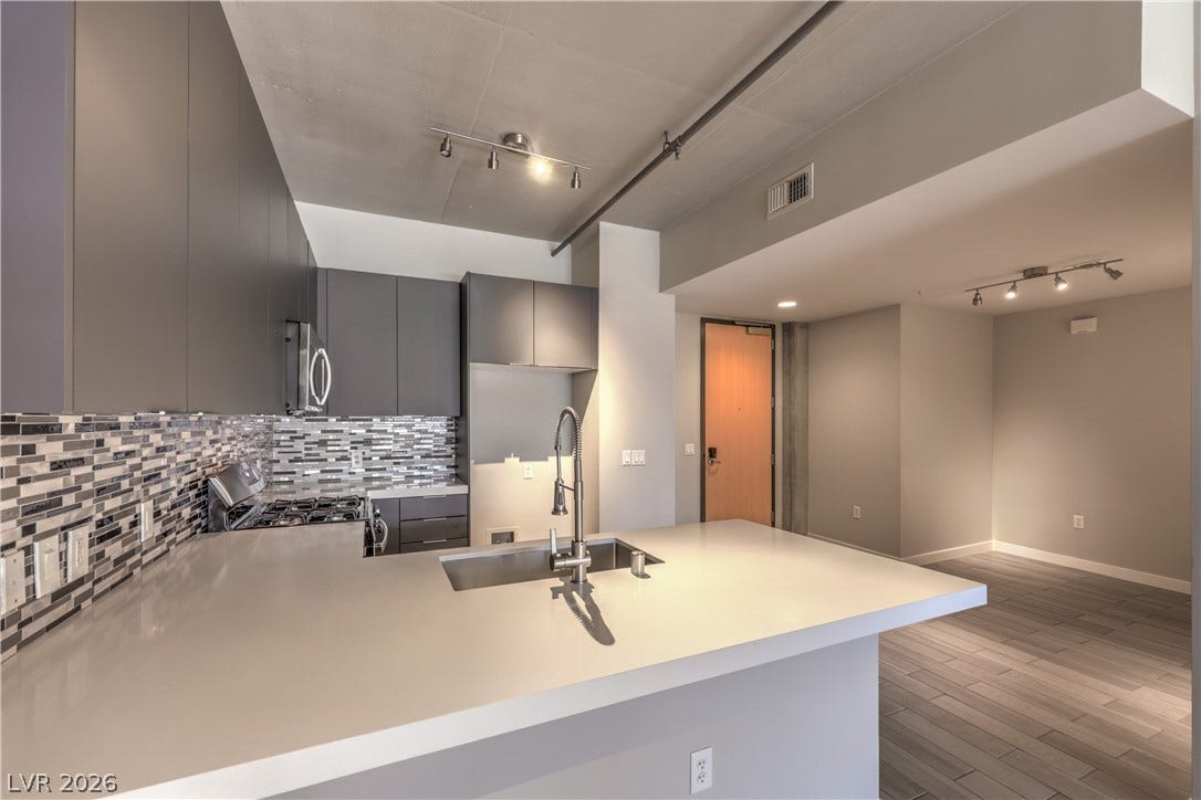 353 E Bonneville Avenue, #754, Las Vegas, NV 89101 Sleek Modern Kitchen features Quartz Countertops, Decorative Tile Backslash, Breakfast Bar, Stainless-Steel Gas Range, Dishwasher, and Microwave