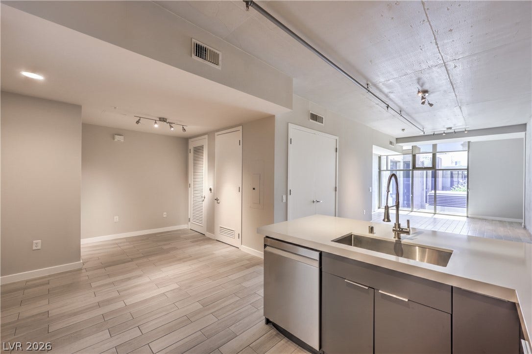 353 E Bonneville Avenue, #754, Las Vegas, NV 89101 Sleek Modern Kitchen features Quartz Countertops, Decorative Tile Backslash, Breakfast Bar, Stainless-Steel Gas Range, Dishwasher, and Microwave