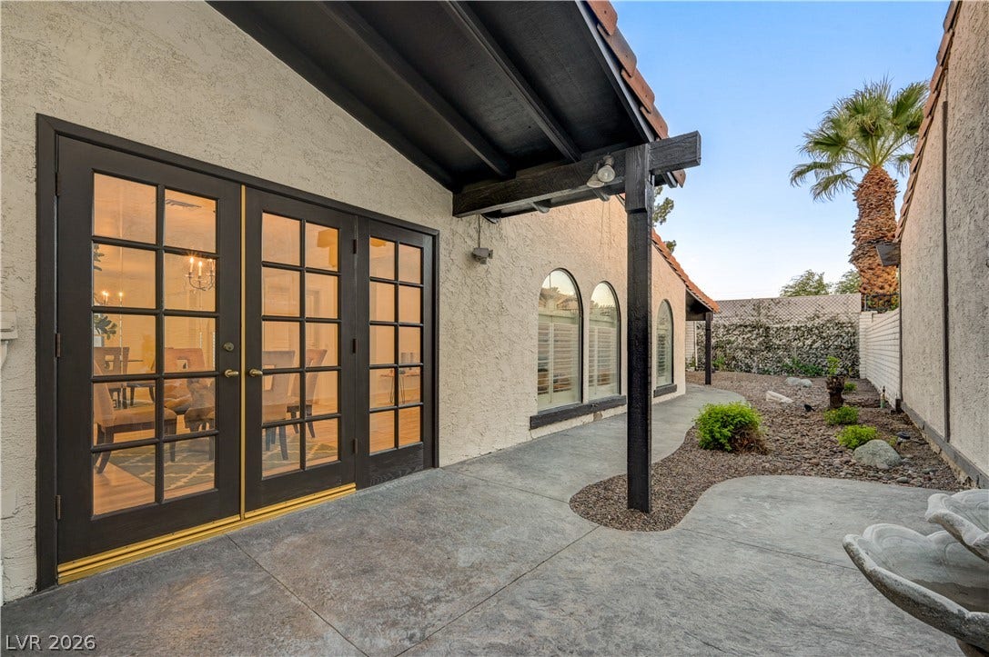 3005 Plaza De Rosa, Las Vegas, NV 89102 A textured concrete patio sits sheltered beneath a deep overhang alongside classic French doors.
