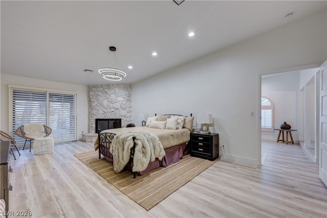 3005 Plaza De Rosa, Las Vegas, NV 89102 A stone fireplace adds cozy architectural character to this bedroom featuring wood-look flooring.