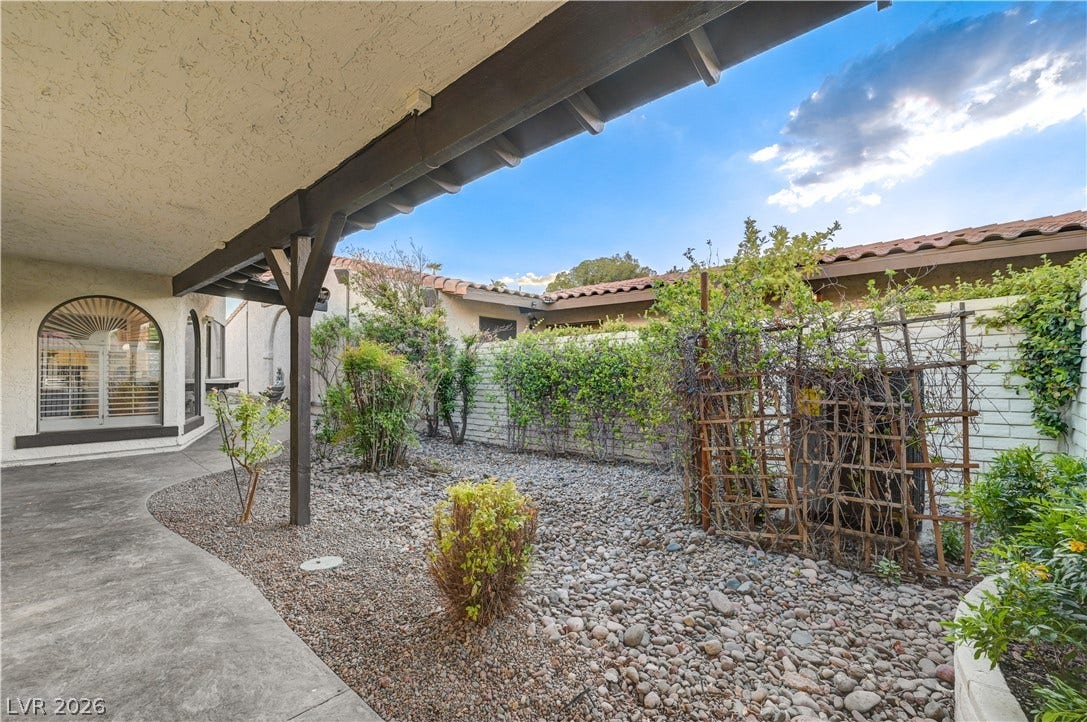 3005 Plaza De Rosa, Las Vegas, NV 89102 A covered concrete walkway runs alongside a private courtyard filled with desert-inspired stone landscaping.
