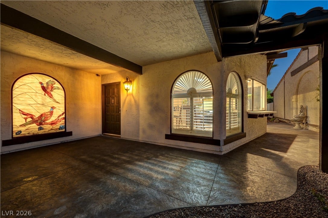 3005 Plaza De Rosa, Las Vegas, NV 89102 Stamped concrete floors and arched windows with plantation shutters frame this welcoming covered entry.
