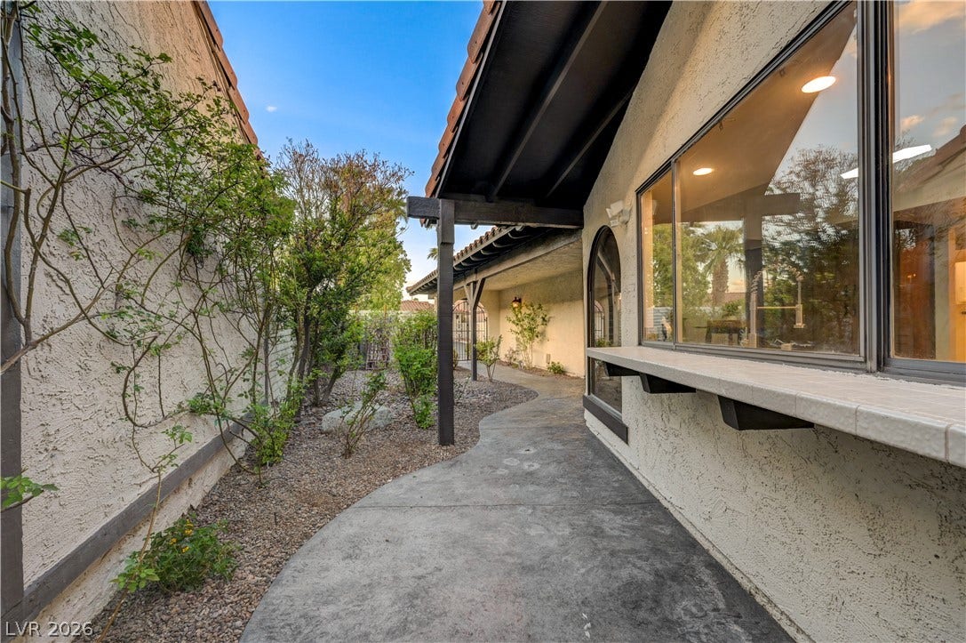 3005 Plaza De Rosa, Las Vegas, NV 89102 A curved concrete path winds through landscaped side yards under deep roof overhangs.