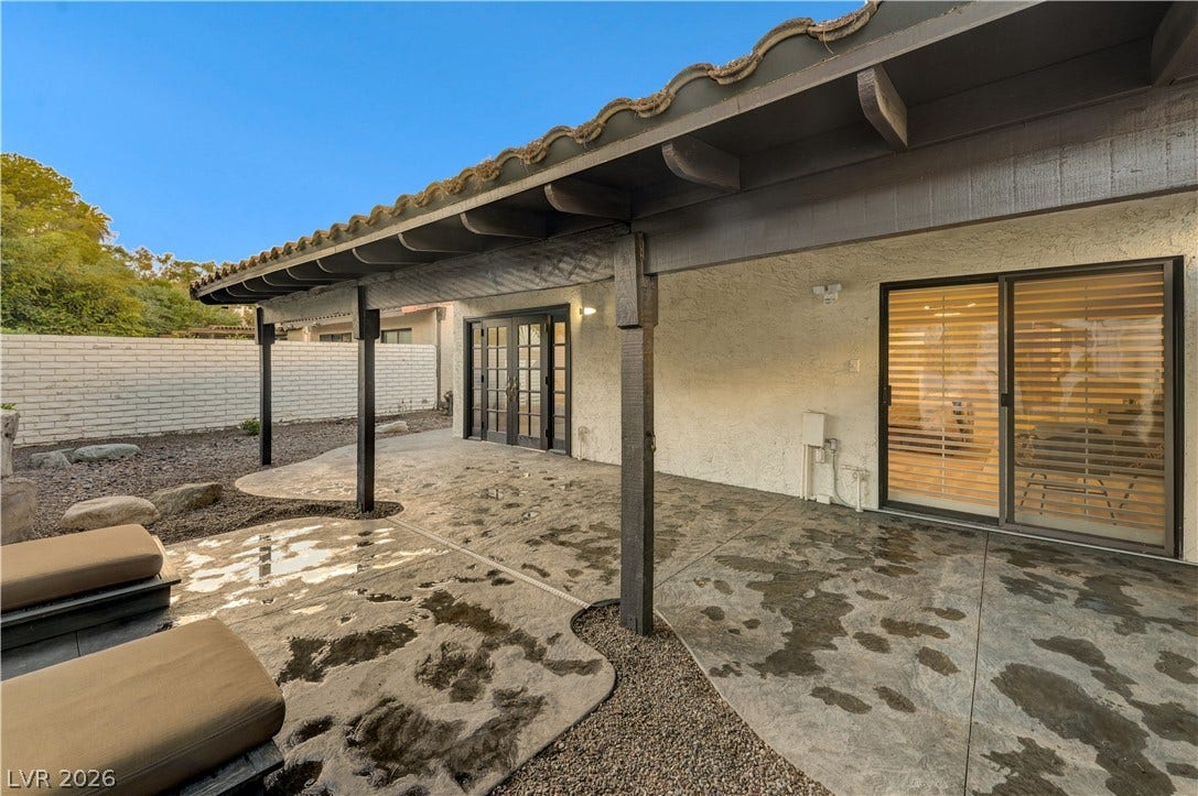 3005 Plaza De Rosa, Las Vegas, NV 89102 A spacious covered patio features stained concrete flooring and exposed ceiling beams alongside stucco walls.