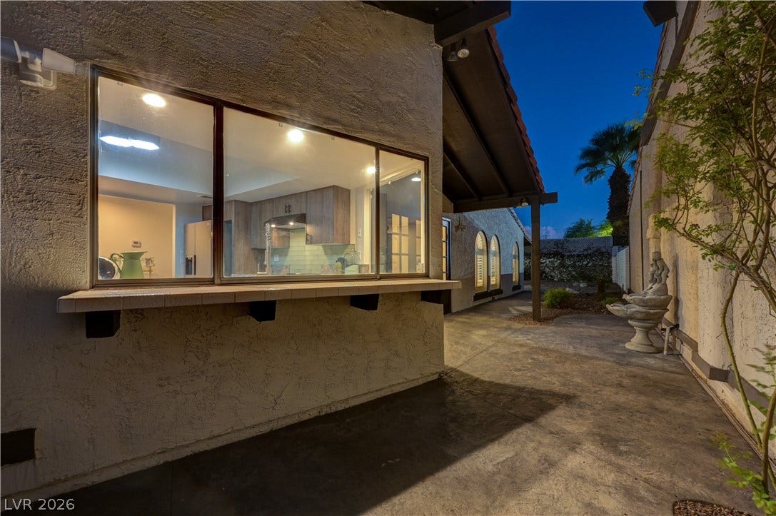 3005 Plaza De Rosa, Las Vegas, NV 89102 Stucco exterior finishes and tiled pass-through ledge frame the kitchen window at twilight.