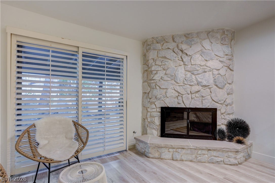 3005 Plaza De Rosa, Las Vegas, NV 89102 A floor-to-ceiling stone fireplace anchors this living space next to large sliding doors.