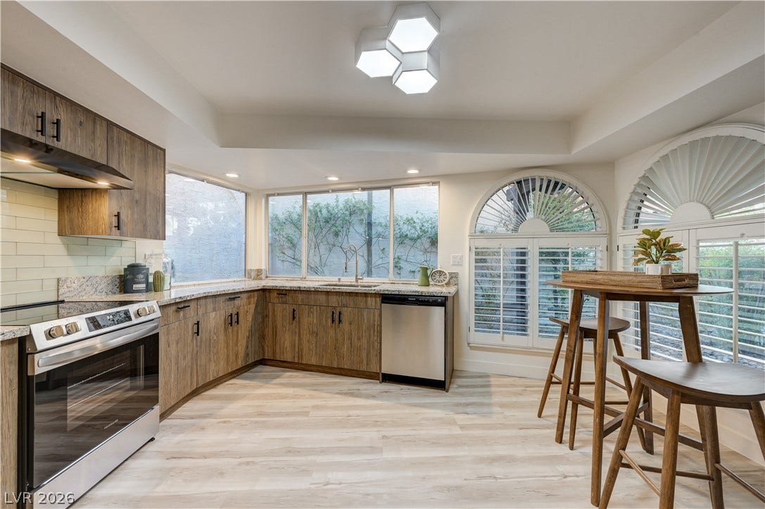 3005 Plaza De Rosa, Las Vegas, NV 89102 Rich wood cabinets and stone countertops frame the wide windows in this modern kitchen.