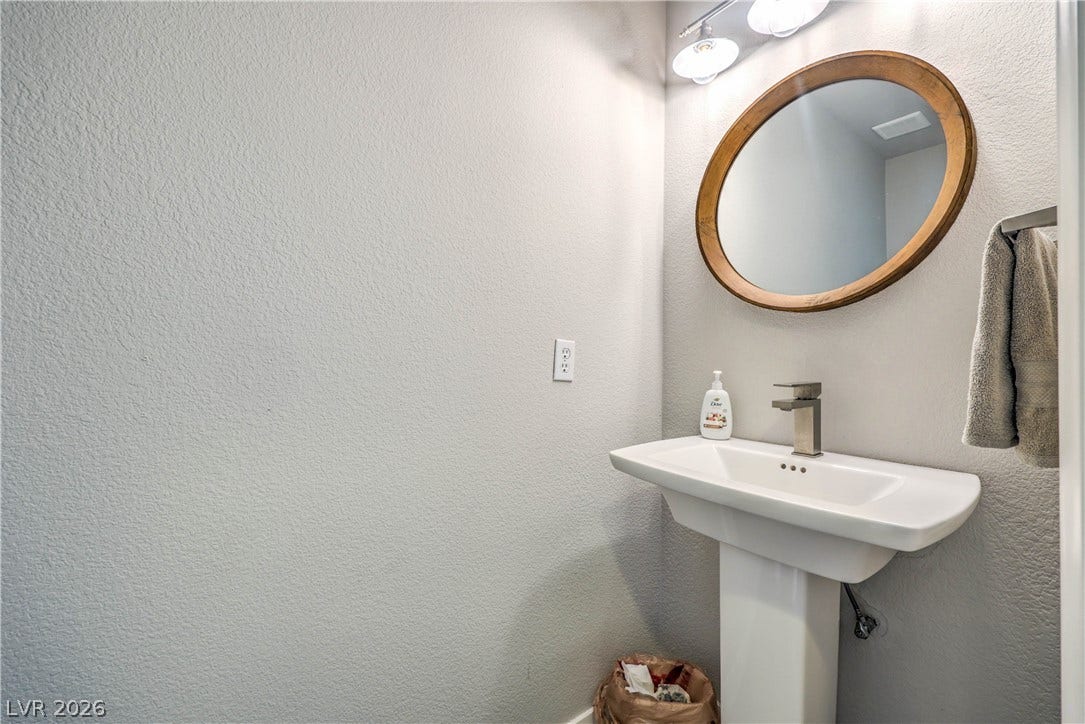 1863 Bogey Way, Henderson, NV 89074 A classic pedestal sink paired with a round wood-framed mirror shapes this powder room.