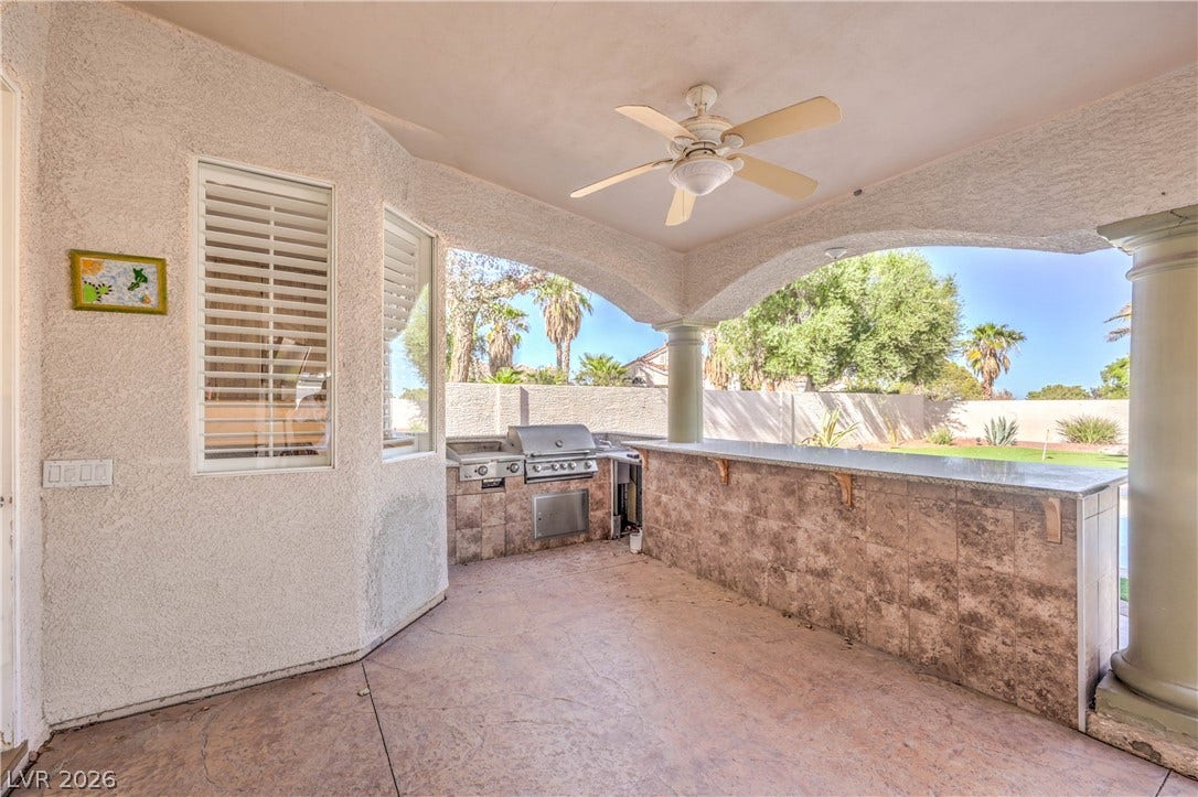 1863 Bogey Way, Henderson, NV 89074 An arched covered patio features a built-in outdoor kitchen with stone counters and tiled accents.