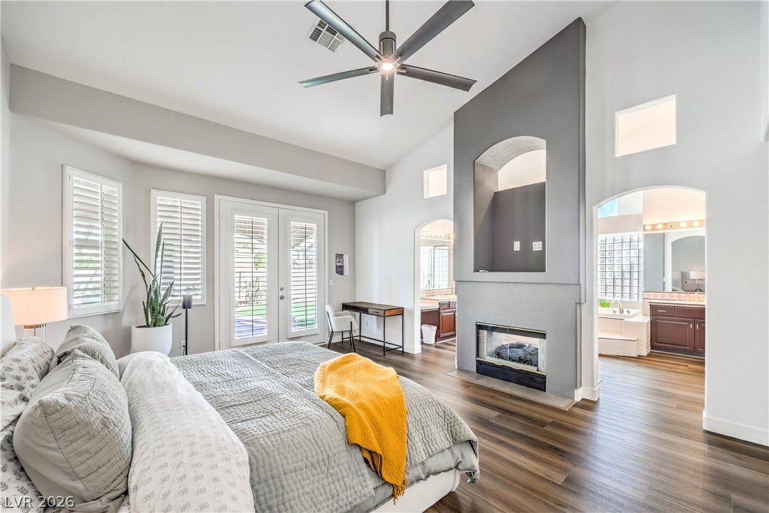 1863 Bogey Way, Henderson, NV 89074 High vaulted ceilings and a modern fireplace anchor this spacious primary suite with wood flooring.
