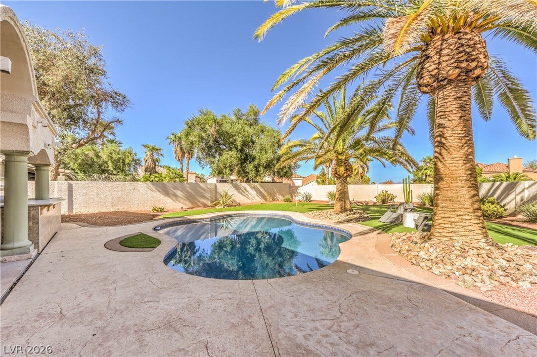 1863 Bogey Way, Henderson, NV 89074 Mature palm trees frame a sparkling swimming pool surrounded by textured concrete decking.