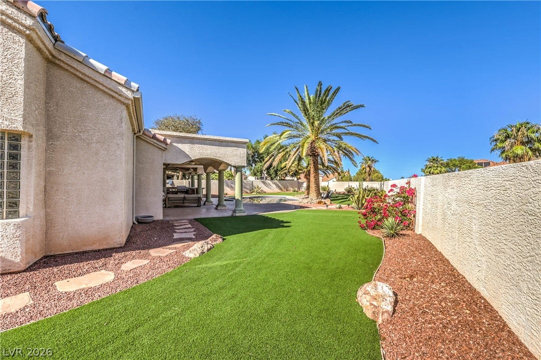 1863 Bogey Way, Henderson, NV 89074 A private backyard oasis features a manicured lawn alongside stucco walls and a covered patio.