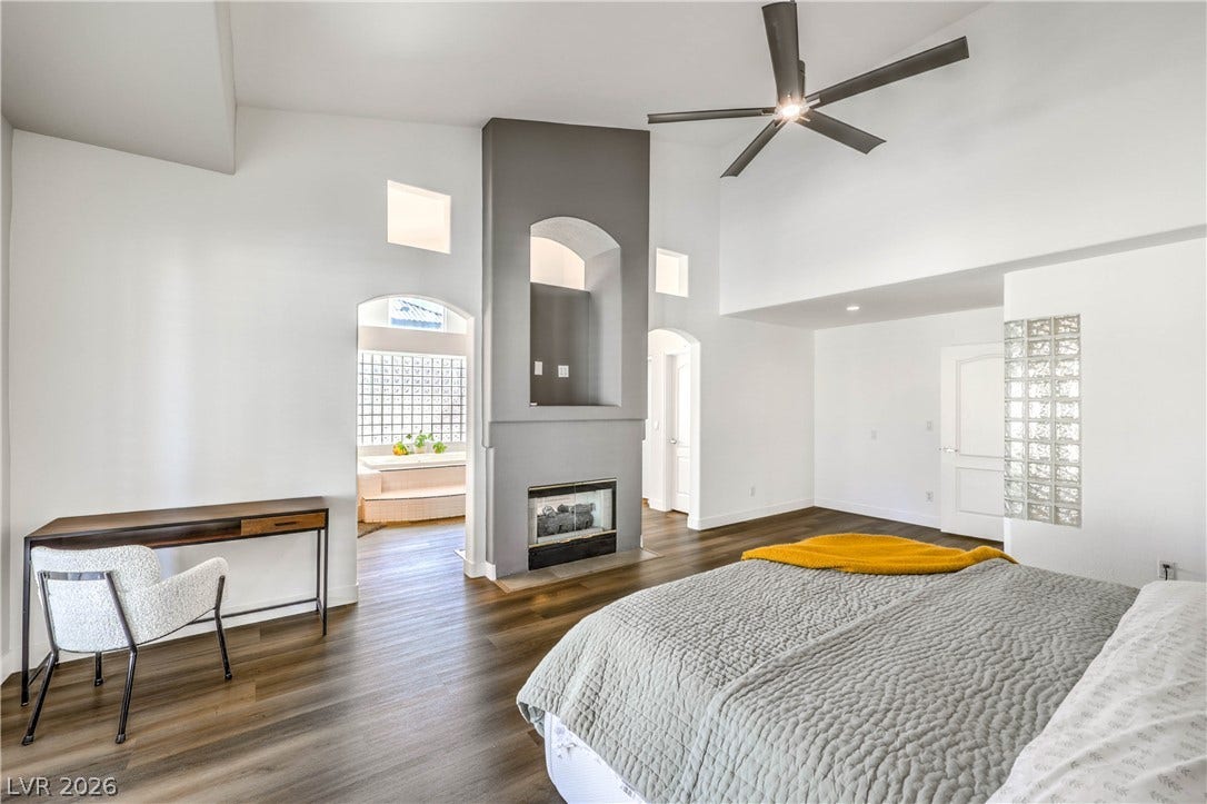 1863 Bogey Way, Henderson, NV 89074 A modern fireplace structure anchors this vaulted bedroom featuring rich wood-look flooring.