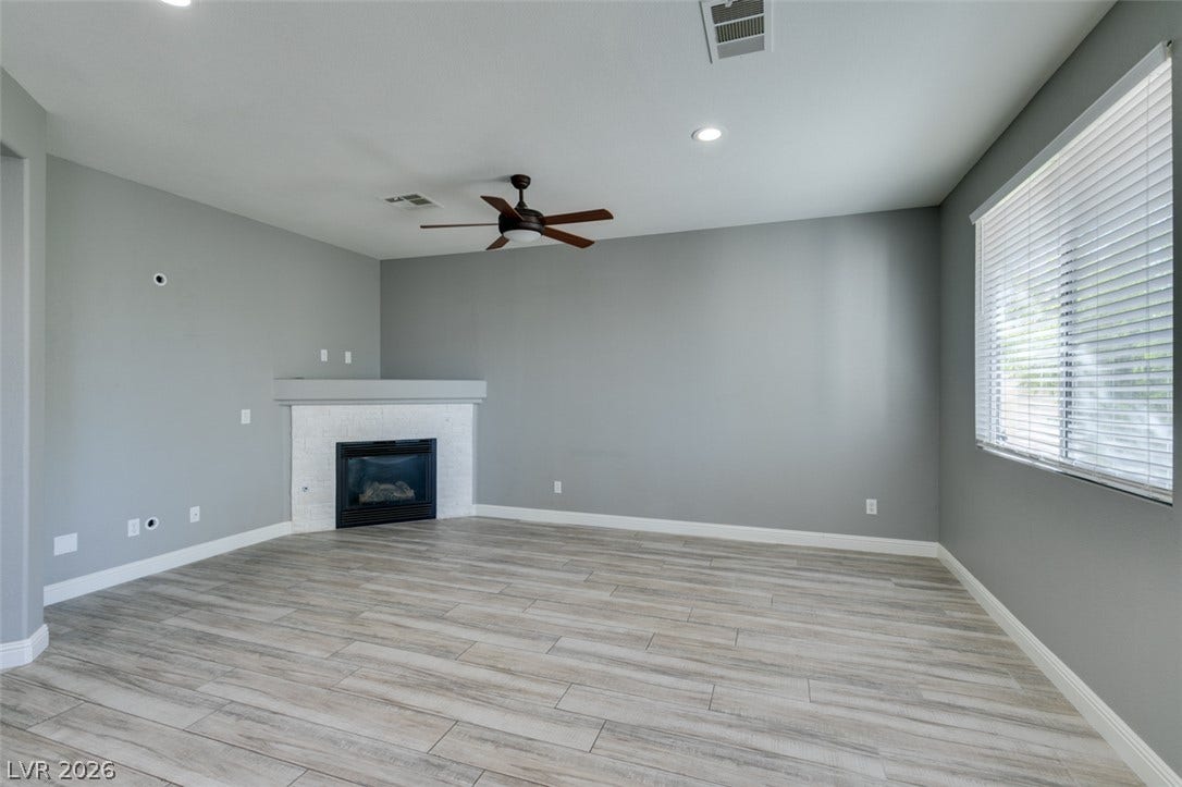 An inviting corner fireplace and textured wood-look flooring anchors this versatile living space.
