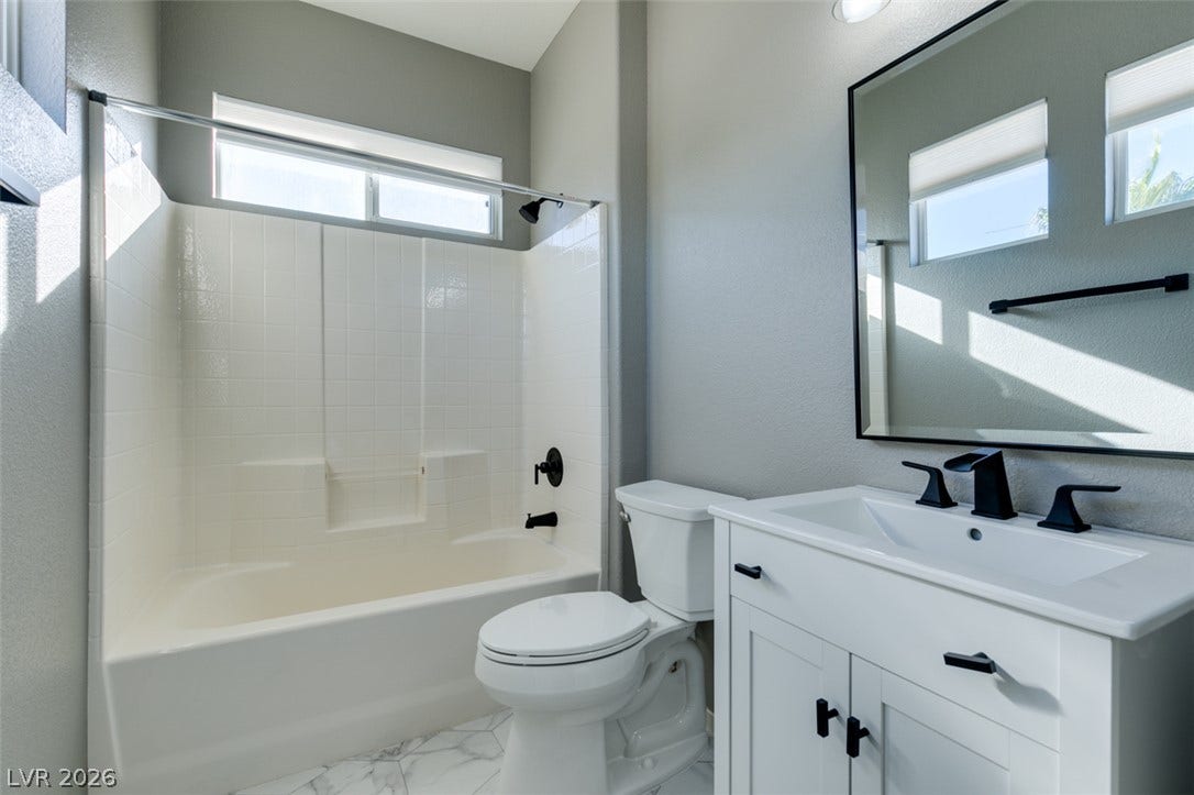 Modern fixtures and clean lines define this refreshed bathroom with marble-patterned tile flooring.