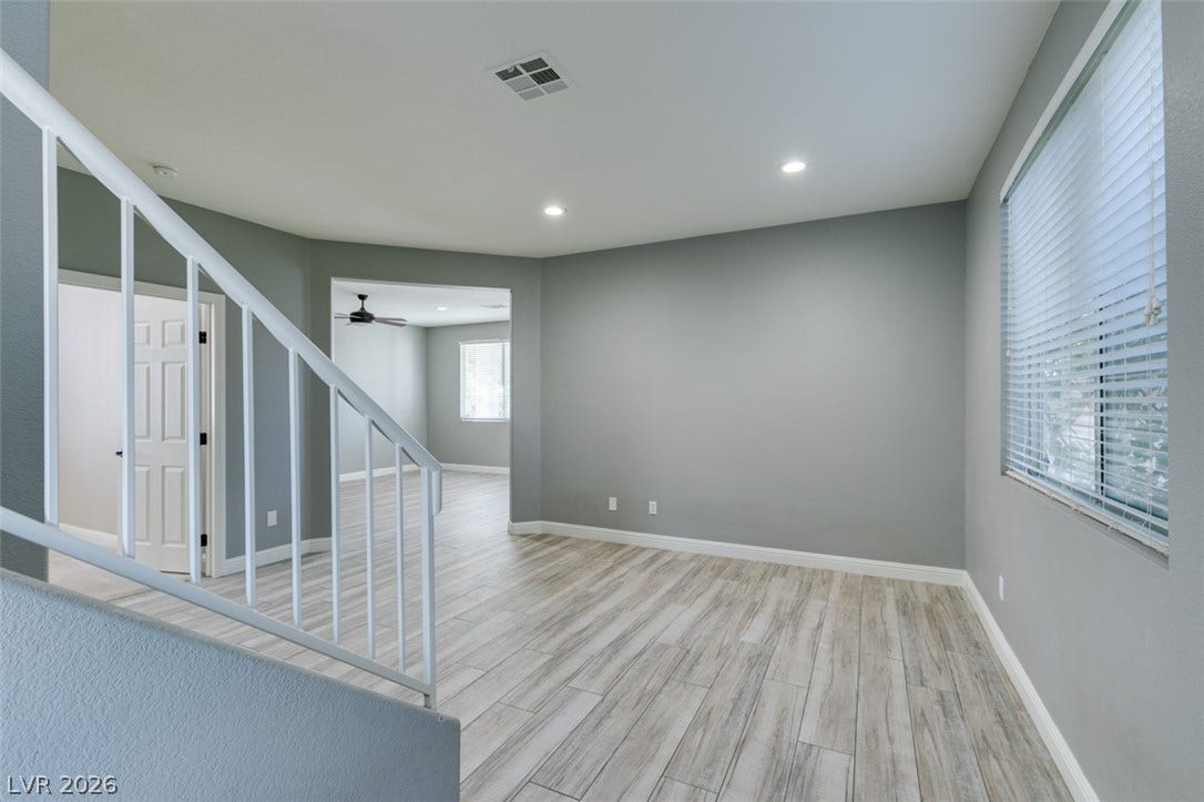 Clean lines and wood-look flooring define this open living space anchored by a modern staircase.
