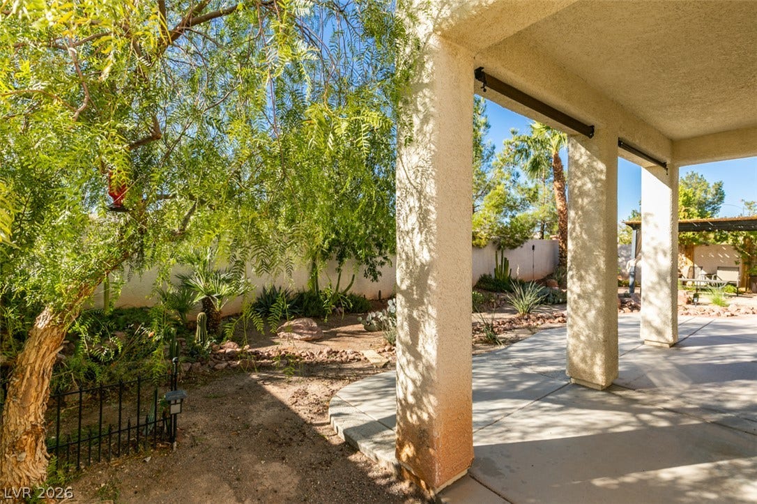 Shaded concrete pillars frame a view of the desert landscaped backyard.