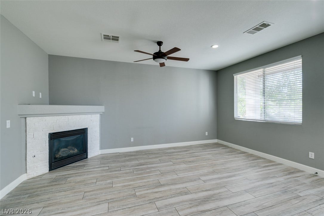 A corner masonry fireplace anchors this versatile space, highlighted by neutral flooring.