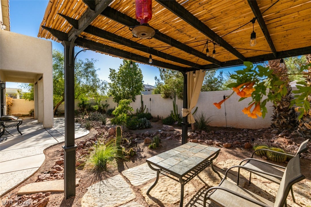 A shaded pergola overlooks a desert-landscaped backyard with flagstone pathways and native plantings.