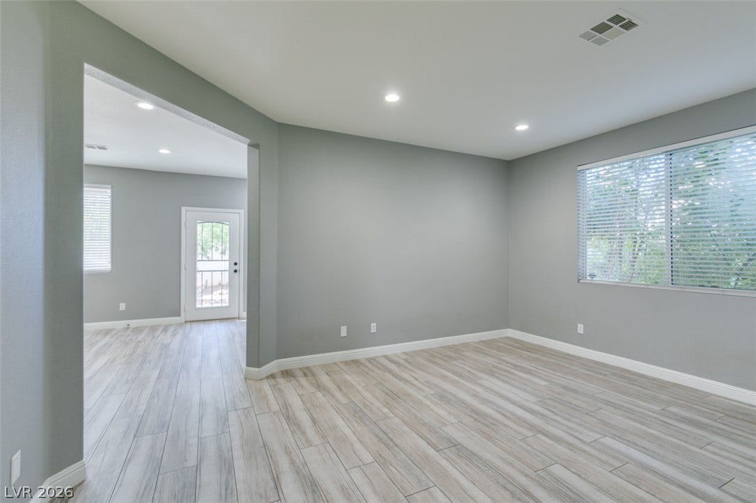 Recessed lighting illuminates wood-look flooring and a wide entryway in a versatile living space.