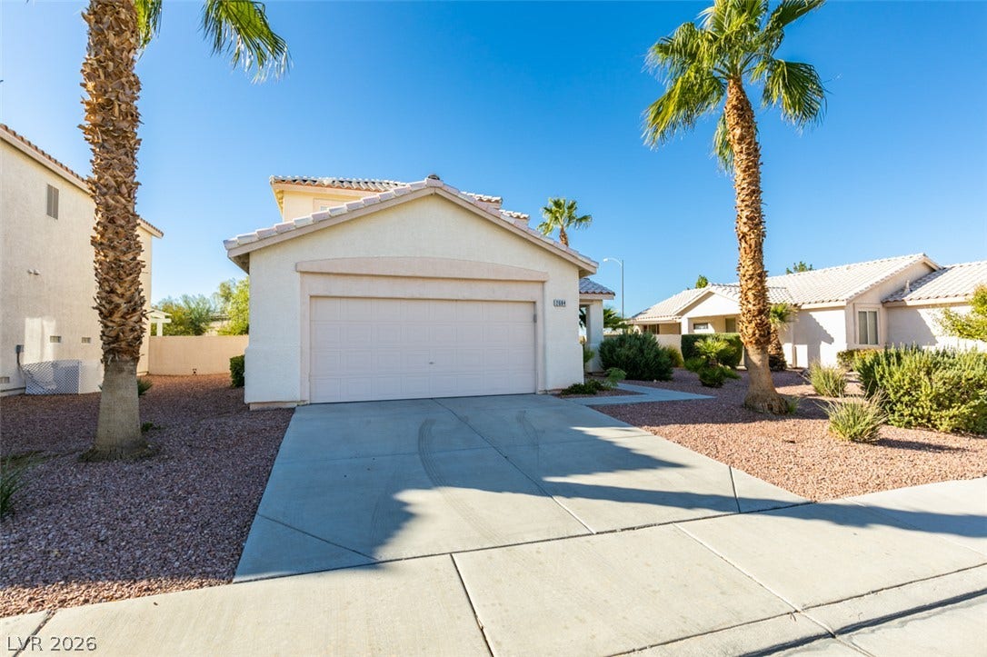 A spacious concrete driveway leads to the attached two-car garage under a tiled roofline.