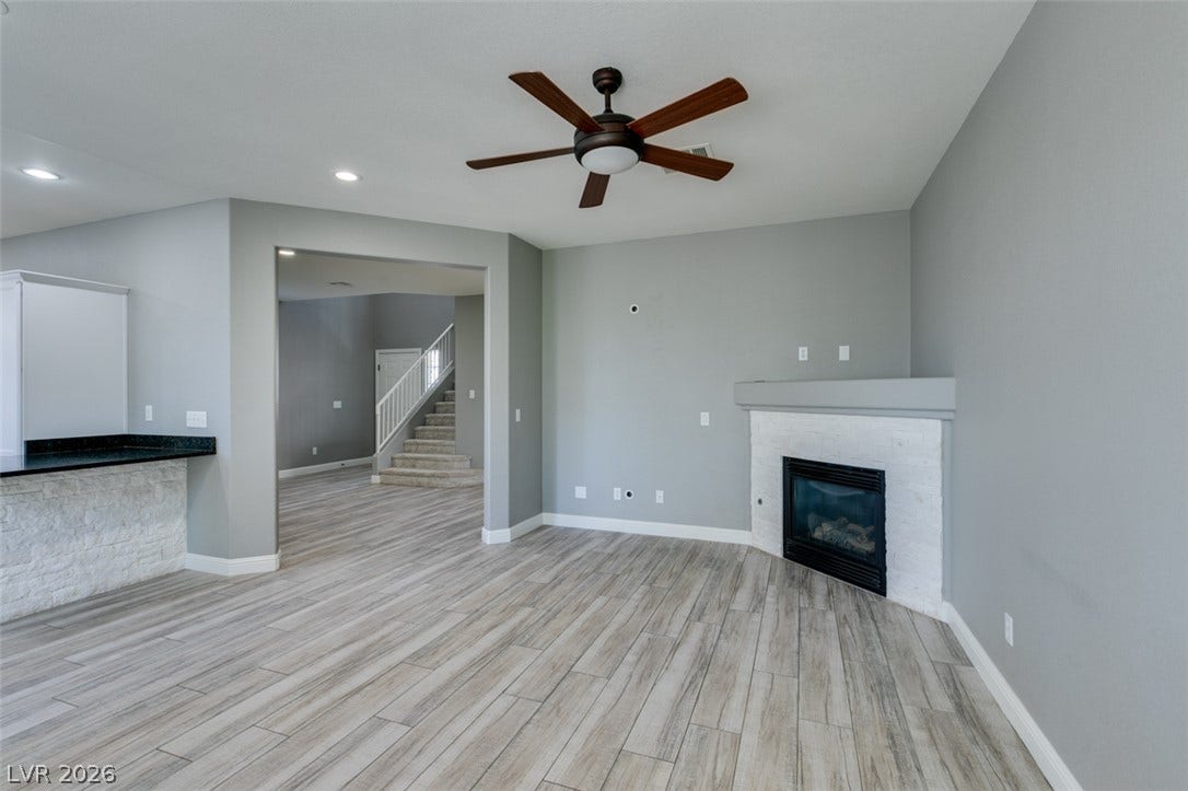 An inviting corner fireplace and textured wood-look flooring anchors this open-concept space.