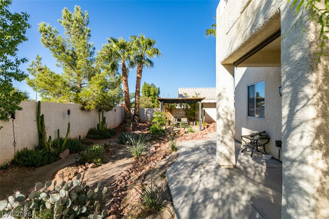 Desert landscaping and palm trees line the walkway alongside this stucco residence.