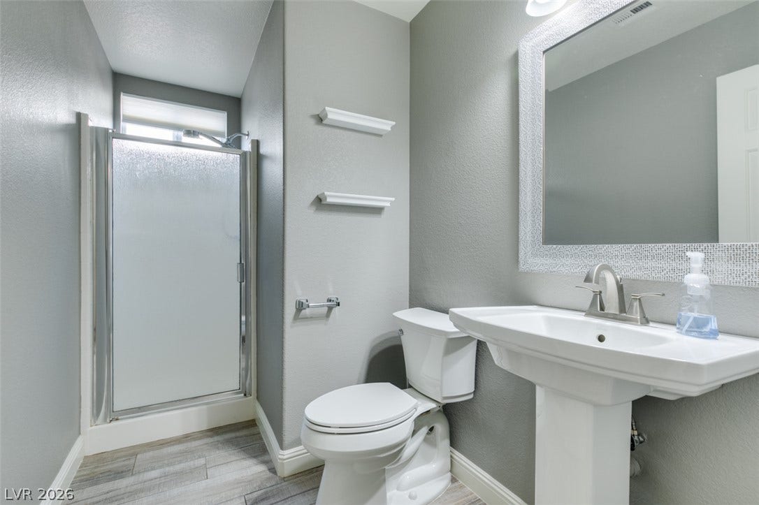 A pedestal sink, modern toilet, and walk-in shower accent this updated bathroom space.