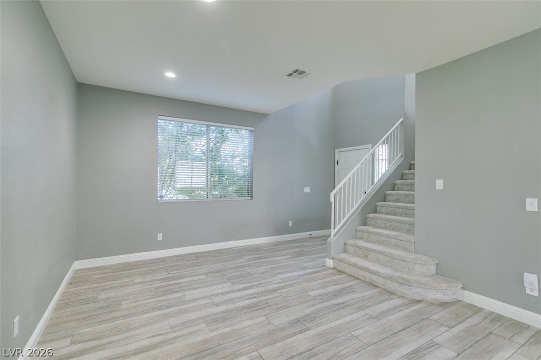 An open floorplan design highlights tile flooring and a carpeted staircase leading upward.