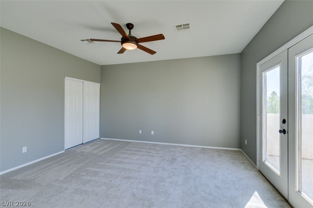 Glass panel doors open to the outside from this carpeted bedroom.