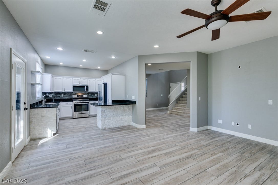 Seamless flow connects the airy kitchen and living areas over stylish plank flooring.