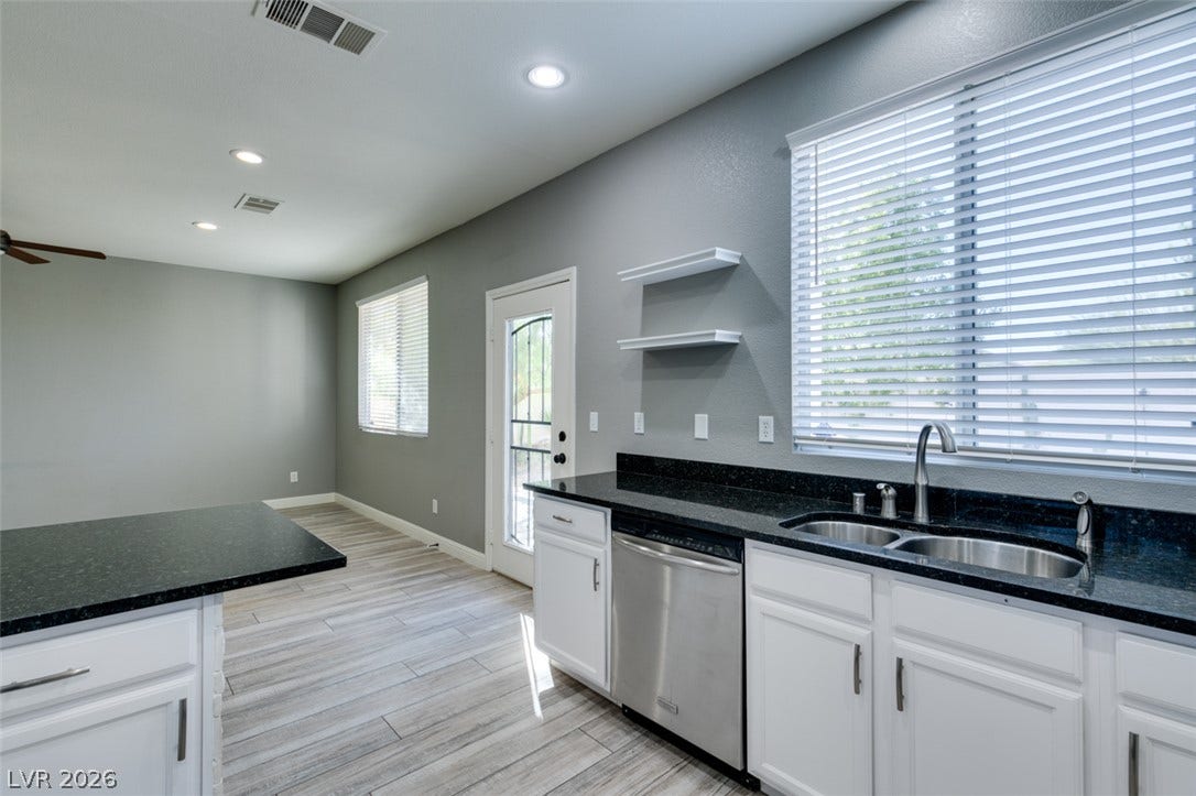 Polished granite countertops and clean white cabinetry highlight this open-concept culinary space.