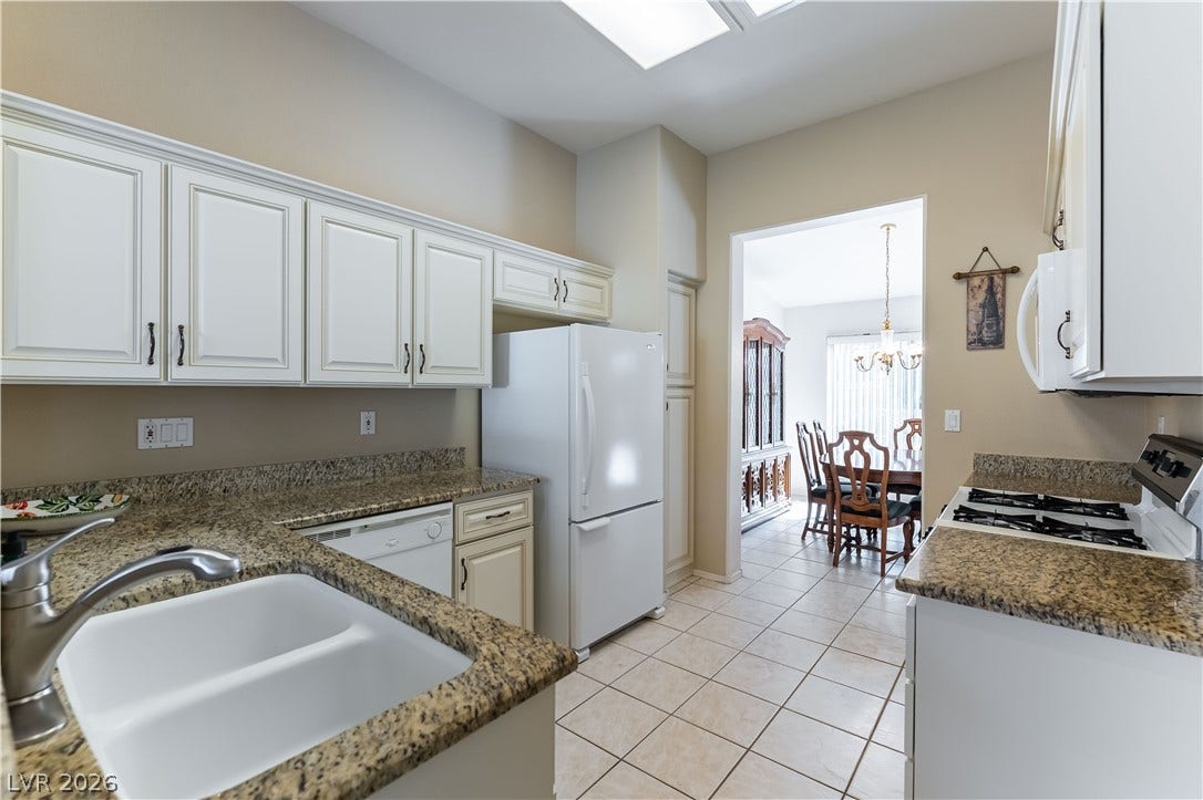 10005 Arbuckle Drive, Las Vegas, NV 89134 Polished granite countertops and classic white cabinetry define this functional, well-lit kitchen space.