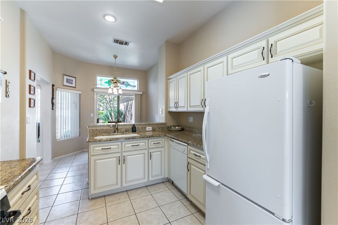 10005 Arbuckle Drive, Las Vegas, NV 89134 Tiled flooring and granite countertops anchor this classic kitchen under high ceilings.