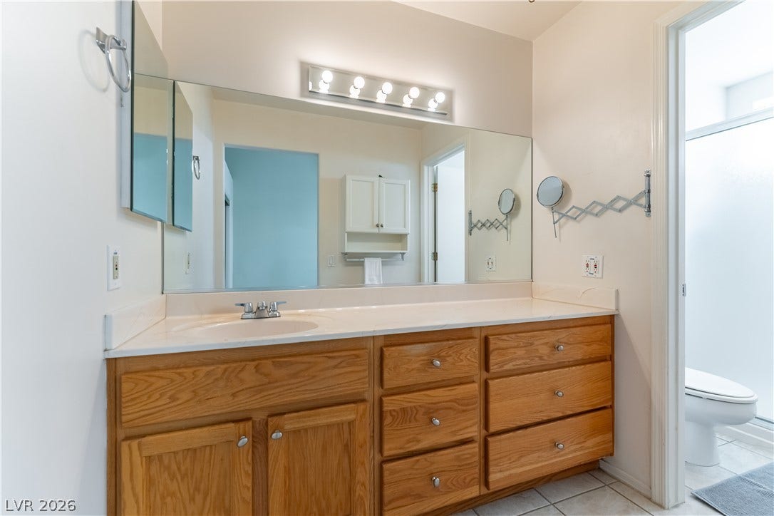 10005 Arbuckle Drive, Las Vegas, NV 89134 An expansive vanity mirror sits above classic wood cabinetry in this well-appointed bathroom.