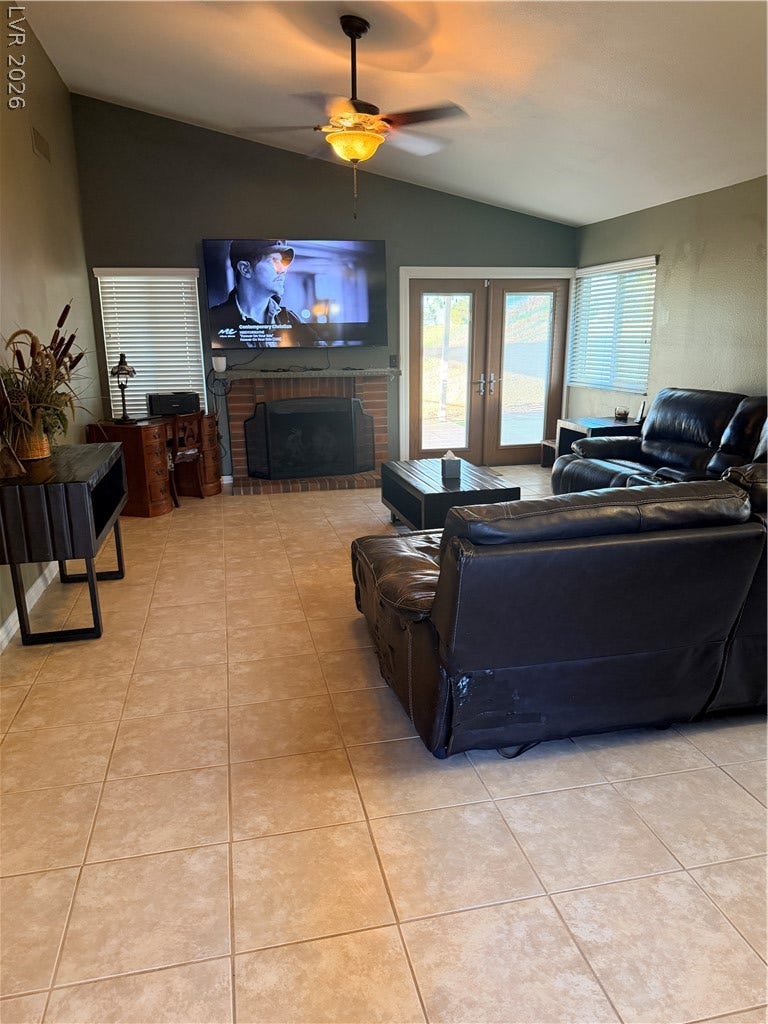 3126 Belvedere Drive, Henderson, NV 89014 Tiled flooring anchors this living space accented by a classic brick fireplace and glass doors.