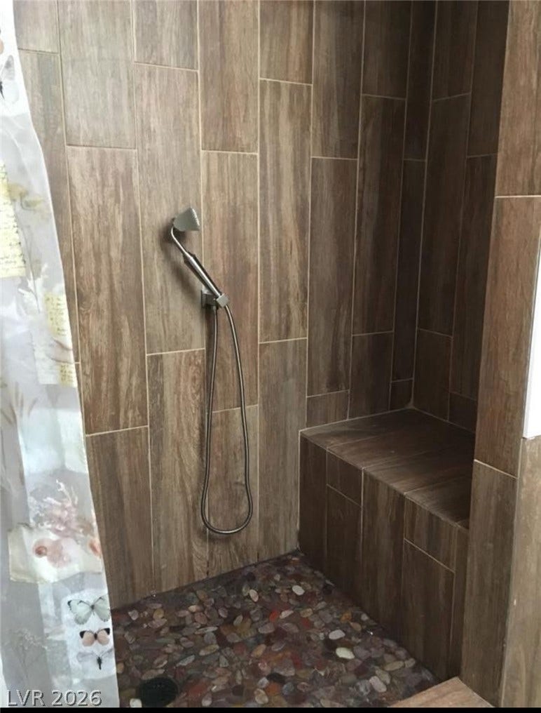 3126 Belvedere Drive, Henderson, NV 89014 Rich wood-look tile walls pair with a textured pebble floor in this walk-in shower.