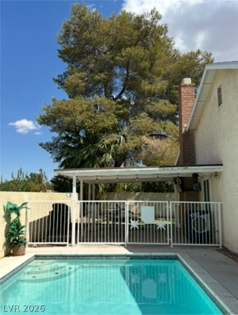 3126 Belvedere Drive, Henderson, NV 89014 Mature trees frame the concrete pool decking and secure safety fencing in the backyard.