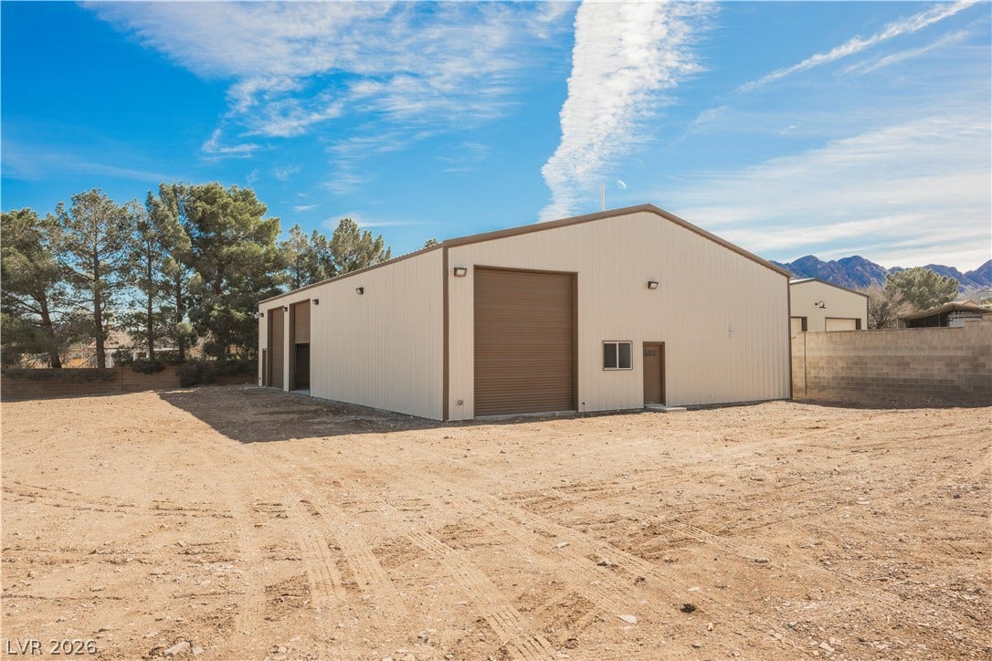 601 Sandy Drive, Henderson, NV 89002 A spacious metal workshop features multiple roll-up doors and a generous dirt lot.