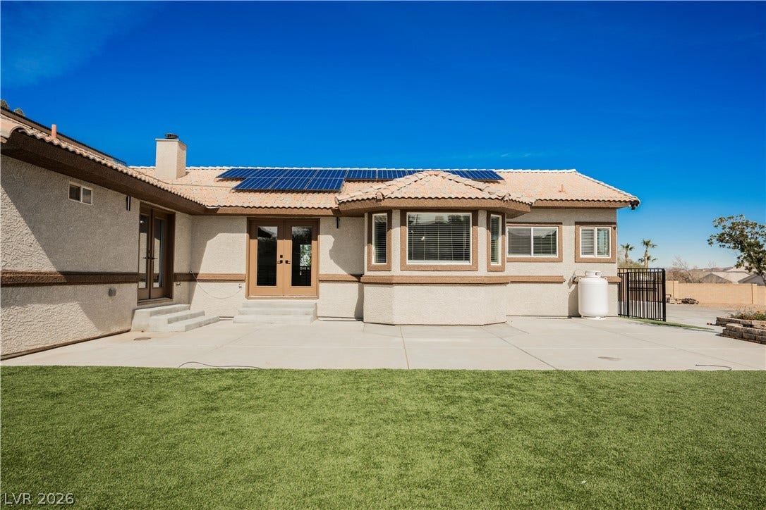 601 Sandy Drive, Henderson, NV 89002 Solar panels sit atop a tiled roof overlooking a spacious paved patio and grassy lawn.