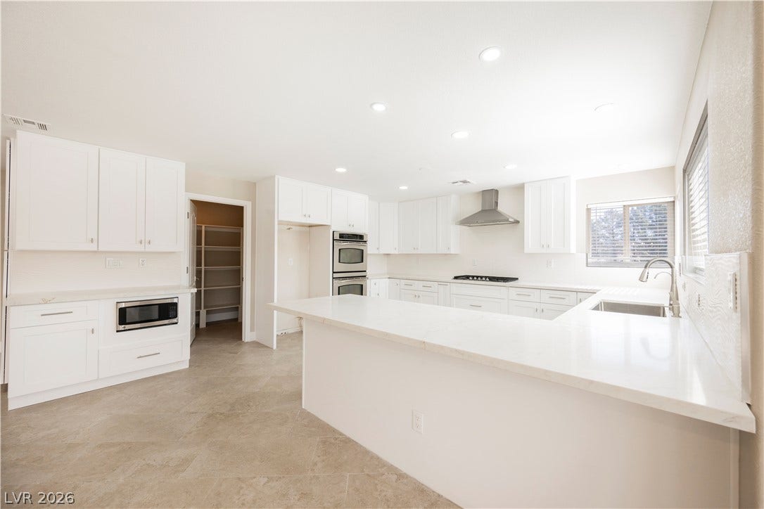601 Sandy Drive, Henderson, NV 89002 Gleaming stone countertops and pristine cabinetry define this airy kitchen layout with walk-in pantry access.