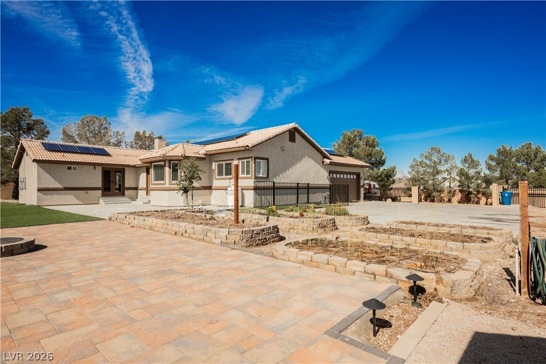 601 Sandy Drive, Henderson, NV 89002 An expansive paved patio extends from the stucco exterior under clear blue desert skies.