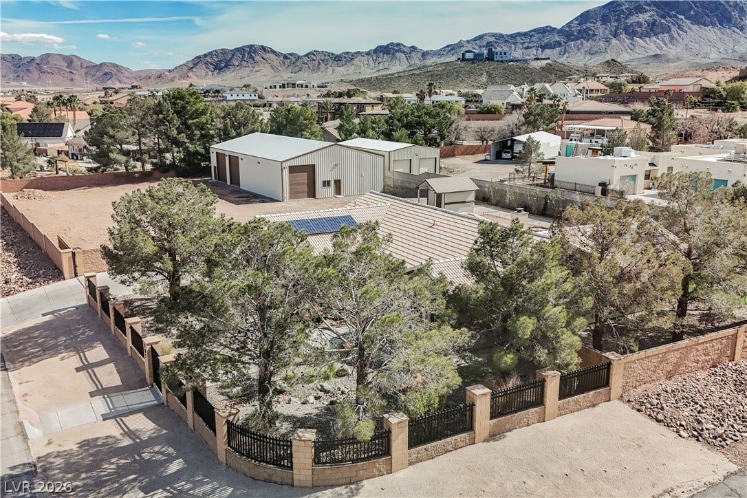 601 Sandy Drive, Henderson, NV 89002 A fenced residential property sits framed by mature trees with rugged mountain views beyond.